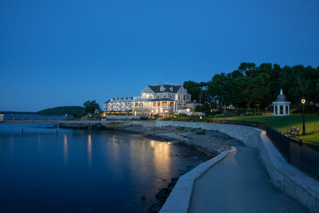Bar Harbor Inn illuminated at dusk beside calm water